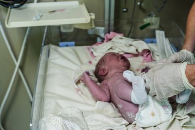 Hastanede dokunaklı bir doğum anı. Doktorlar ve çalışanlar anneye yardım ederken baba da yeni doğanların mutluluğunu paylaşıyor..