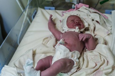 Hastanede dokunaklı bir doğum anı. Doktorlar ve çalışanlar anneye yardım ederken baba da yeni doğanların mutluluğunu paylaşıyor..