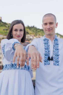 Damat geline evlilik teklifi ederken, bir nişan yüzüğü takıp nazikçe yanağından öpüyor. Çift geleneksel Ukrayna nakışlı düğün kıyafetleri giyer, Tbi 'nin manzaralı arka planına karşı sevgi ve bağlılığı kutlar.