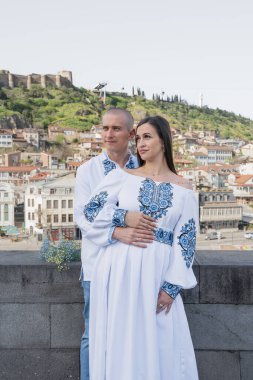 Damat geline evlilik teklifi ederken, bir nişan yüzüğü takıp nazikçe yanağından öpüyor. Çift geleneksel Ukrayna nakışlı düğün kıyafetleri giyer, Tbi 'nin manzaralı arka planına karşı sevgi ve bağlılığı kutlar.