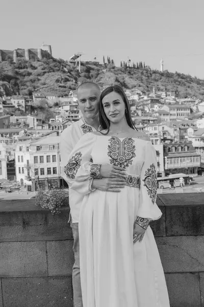Damat geline evlilik teklifi ederken, bir nişan yüzüğü takıp nazikçe yanağından öpüyor. Çift geleneksel Ukrayna nakışlı düğün kıyafetleri giyer, Tbi 'nin manzaralı arka planına karşı sevgi ve bağlılığı kutlar.