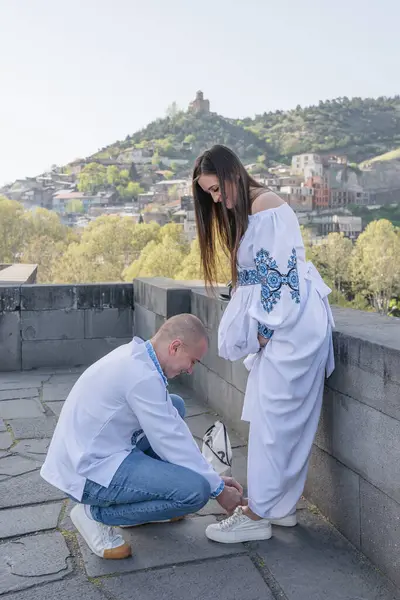 Damat geline evlilik teklifi ederken, bir nişan yüzüğü takıp nazikçe yanağından öpüyor. Çift geleneksel Ukrayna nakışlı düğün kıyafetleri giyer, Tbi 'nin manzaralı arka planına karşı sevgi ve bağlılığı kutlar.