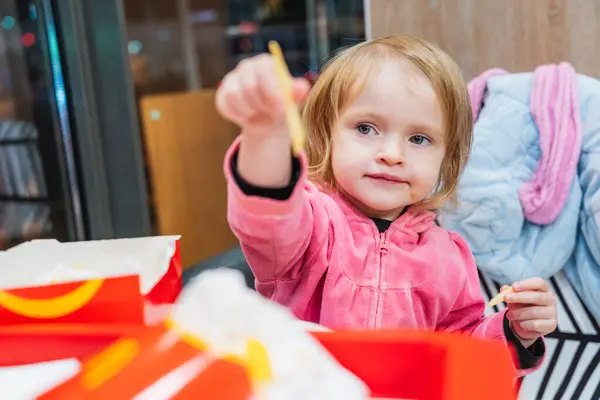 Komik küçük bir kız fast food yiyor, patates kızartması yiyor, hamburger yiyor ve meyve suyu içiyor. Onun şakacı asabiyeti sahneye ekstra bir mizah katıyor..