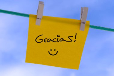 Yellow sticky note with thank you message and smiley face hanging on a clothesline clipart