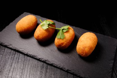 Maydanoz garnitürlü, tahta tabakta jambonlu kroket.