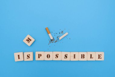 Kırık sigara ve mavi arka planda insanları sigarayı bırakmaya teşvik eden el yapımı Scrabble mektupları..