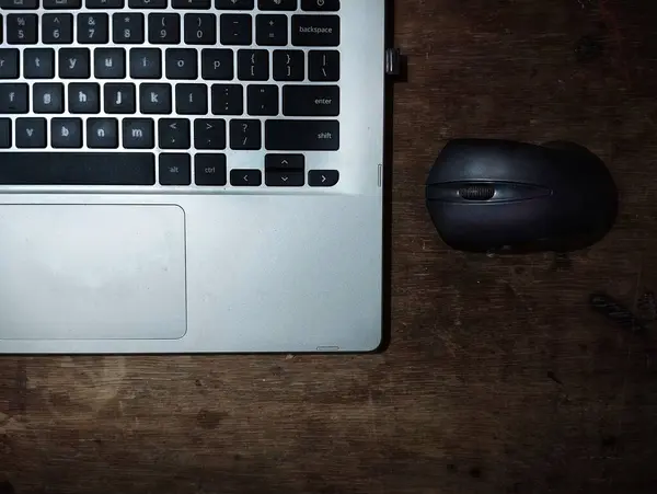 Kahverengi tahta masa arkaplanındaki laptop ve siyah farenin üst görünümü