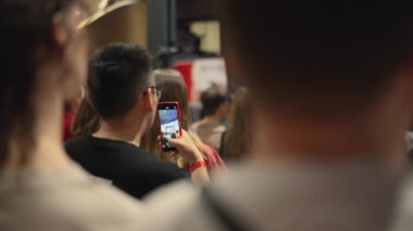 Bir grup insan karanlık bir odada toplanarak, olayın gerçekleşmesi umuduyla ekran aygıtlarına bakıyorlar. Bina heyecan ve eğlenceyle dolu, herkese eğlence sunuyor.