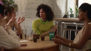 4K homoseksüel insanlar barda konuşuyor ve kokteyl içiyor. Genç lezbiyen kadınlar, eşcinsel erkek konuşuyor ve alkol içiyorlar, kutlama yapıyorlar ve iç kısımda masa başında oturuyorlar. Güzel çok ırklı