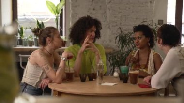 4K Güzel Igbt arkadaşları kokteyl içer ve kafede otururlar. Neşeli kadınlar, tatlı tatlı konuşan, gülümseyen, içki içen ve iç kısımda masa başında oturan erkekler. Grup