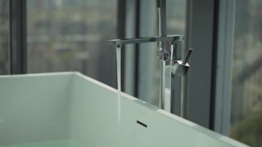 Büyük küveti kısmen suyla dolu modern bir banyo. Suda turuncu bir termometre yüzer. Bu da bebek banyosu hazırlığını gösterir. Bebek bakımı ve hijyen kavramı. Yüksek kalite