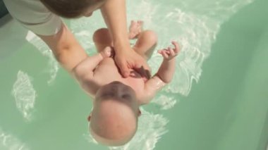 Annem sıcak suda bebeğe özenle bakıyor. Güvenliği, rahatlığı ve temizliği sağlıyor. Bebek rahatlatıcı banyo deneyimini, anne-bebek bağlarını geliştirmeyi ve güvenlik duygusunu güçlendirmeyi seviyor. Yüksek