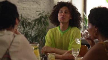 4K homoseksüel insanlar barda konuşuyor ve içki içiyor. Gülen, eğlenen, kokteyl içen ve iç mekanda masa başında oturan eşcinsel, lezbiyen kadınların yakın görüntüsü. lgbt Grubu