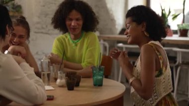 4K Lgbt insanları barda içki içip eğleniyor. Genç, güzel lezbiyen kadınlar, gülümseyerek konuşan, gülen, kokteyl içen ve masada oturan. Bir grup mutlu arkadaş