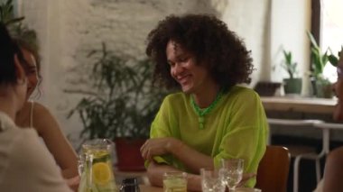 4k Mutlu Igbt insanları konuşuyor ve barda masada eğleniyor. Homoseksüel erkek, gülücükler saçan, sohbet eden, alkollü içecek içen ve iç mekanda masa başında oturan kadınlar. Neşeli arkadaşlar.