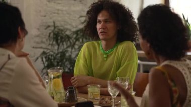 4K homoseksüel insanlar konuşuyor ve barda içeceklerle eğleniyorlar. Genç lezbiyen kadınlar, gülümseyen, kutlayan, kokteyl içen ve masada oturan eşcinsel erkekler. Çoklu grup