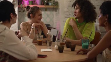 4K Lgbt arkadaşları konuşuyor ve barda kokteyllerle masaya oturuyorlar. Genç, güzel lezbiyen kadınlar, neşeli gülücüklerle geyce konuşmalar, alkol içmeler, iç tarafta masa başında oturmalar. Çok ırklı insanlar grubu