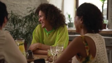 4k genç Igbt arkadaşları bardaki masada eğlenip içki içiyorlar. Güzel lezbiyen kadınlar, gülümseyen, gülen, kokteyl içen ve masada oturan eşcinsel erkekler. Çoklu grup