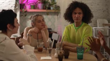 4K Lgbt insanları barda içki içip eğleniyor. Güzel lezbiyen kadınlar, erkekler konuşuyor, gülüyor, kokteyl içiyor ve kafede masa başında oturuyor. Homoseksüel arkadaşlar grubu kutlama yapıyor