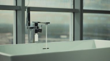 Akan musluktan akan temiz suyla minimalist banyo küveti kurulumu. Bu özenle hazırlanmış banyo, bebeklerin suyla ilk duyusal deneyimlerini teşvik ediyor. Bebek erken gelişimi kavramı. Yüksek kalite 4k