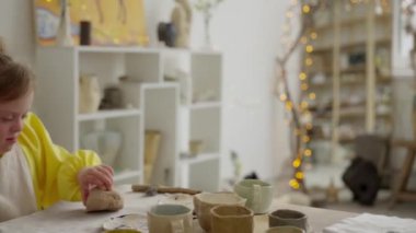 Çömlekçilik dersinde Down sendromlu genç bir kız ilk kez çamura dokunuyor, dikkatle konsantre oluyor. Engelli çocukların yeni materyaller keşfetmede eğitimin rolünü vurgulamak
