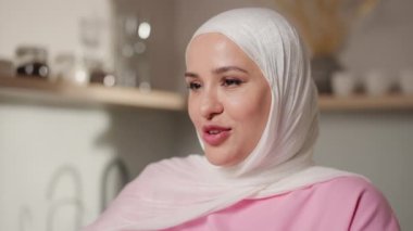 Kamera, beyaz tesettürlü Müslüman kadını mutfaktaki duruşunu göstermek için geri çekiyor. Görüntülü aramaya devam ediyor, anlamlı bir şekilde. Sanal iletişim ve günlük yaşam kavramı