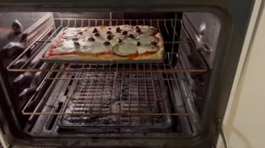 Patlıcan zeytinli ev yapımı pizza ve gaz fırınında mozzarella pişirmek.