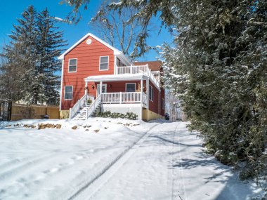 Kırmızı banliyö evi, mavi bir kış günü, kar altında.