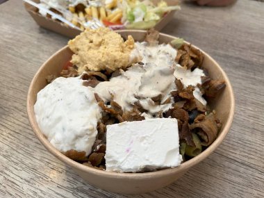 Türk kebabı peynir, sos ve ahşap masada humus ile servis edilir.