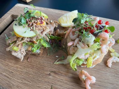 Tahtada karides ve sebzeli iki tarafı açık sandviç..