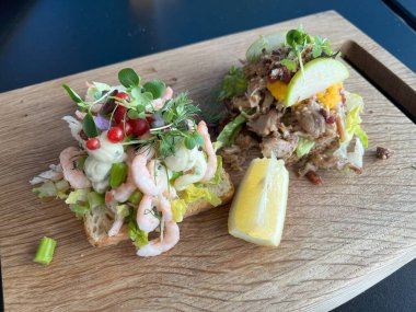 Tahtada karides ve sebzeli iki tarafı açık sandviç..