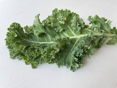 Kale leaf salad vegetable on white wooden table. Creative layout made of kale closeup. Food concept. clipart