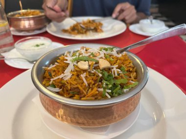 Restoran masasındaki bakır kasede pirinç biryani 'si. Tavuk biryani. Kuzu biryani.