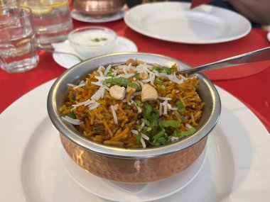 Restoran masasındaki bakır kasede pirinç biryani 'si. Tavuk biryani. Kuzu biryani.