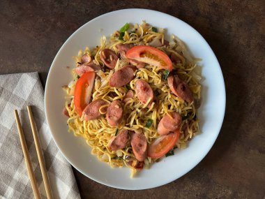 Mie goreng sosis veya sosisli kızarmış erişte, Endonezya 'nın sosis, sosis, sosis ve Çin lahanasıyla pişirilen ve siyah arka planda servis edilen bir şehriye türüdür..