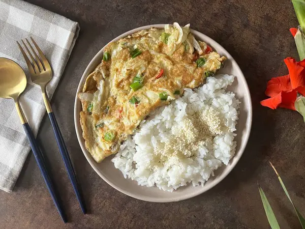 Ucuz ve basit yiyecekler. Susamlı beyaz pirinç ve tavuklu sebze dolu omlet..