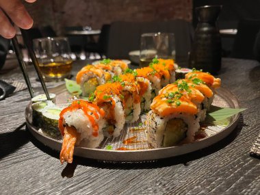 Bir tabak suşi sarması. Suşi, bir restorandaki ahşap bir masada bir tabağa konmuş.