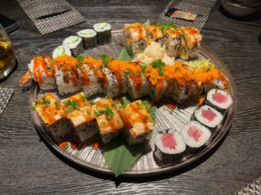 Bir tabak suşi: somon, ton balığı ve ahşap masada soya sosuyla servis edilen bazı vejetaryen seçenekler de dahil olmak üzere çeşitli suşi çeşitleri.