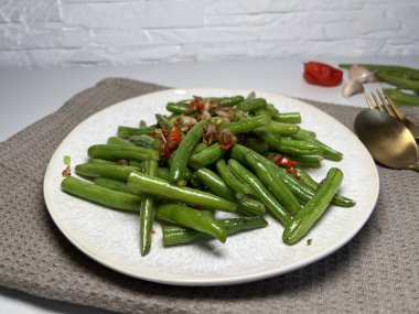 Sarımsaklı yeşil fasulye ve beyaz tabakta kırmızı biber. Asya tarzı yemekler.. 