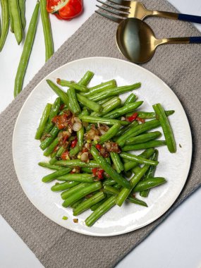 Sarımsaklı yeşil fasulye ve beyaz tabakta kırmızı biber. Asya usulü yemek. Üst görünüm