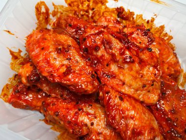 Baharatlı baharatlı tavuk kanatları ve beyaz arka planda baharatlar. Hızlı pişirme. Çiğ marine edilmiş tavuk eti..