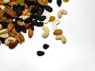 Karışık fındık, badem, ceviz, kaju, fındık, kuru erik ve kuru üzüm. Farklı fındık karışımı. Beyaz arka planda çeşitli fındıklar ve kurutulmuş meyveler.