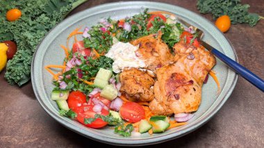 A vibrant and colorful salad plate with grilled chicken, fresh vegetables, and creamy dressing. The plate is set on a rustic background with additional ingredients like lemon, tomatoes, and kale clipart