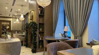Vilnius, Litvanya. Ocak 04, 2025. Zarif dekorları olan rahat ve davetkar bir restoran. Dışarıda kar manzarası olan lüks koltuklar, masalar ve dekoratif lambalarla donatılmış..