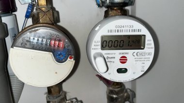 Kaunas, Litvanya. 13 Kasım 2024. Bir evde tüketilen su miktarını ölçmek için iki su ölçer kullanıldı. Mekanik arama ve dijital modeli olan eski bir model.