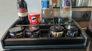 Varşova, Polonya. Kasım 02, 2024. Çeşitli imkanları olan bir otel odası mini barı. Sade bir kahve makinesi, bir şişe su, şarap, kahve kapsülleri ve diğer atıştırmalıklar.