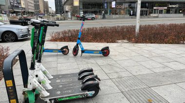 Varşova, Polonya. Kasım 01, 2024. Şehrin kaldırımına park etmiş bir dizi elektrikli scooter. Mobiletler düzgünce dizilmiş ve kiralanmaya hazır görünüyor..