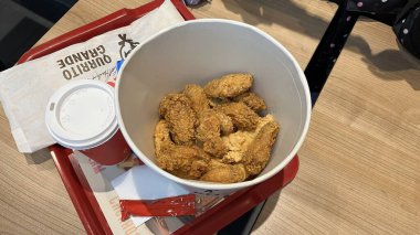 Varşova, Polonya. Kasım 01, 2024. Fast food restoranından kırmızı tepside yemek. Yemek bir kova kızarmış tavuk içeriyor.