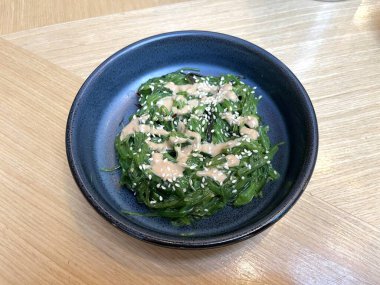 Japon restoranının masasındaki kasede susam tohumlu Goma Dare soslu yosun salatası.
