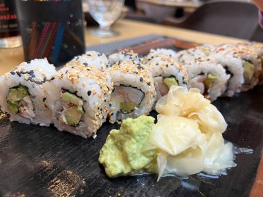Japon restoranındaki suşi rulosunu siyah tabakta kapat.